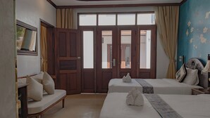A hotel room with two beds, a bench, a TV, and a large window with curtains.