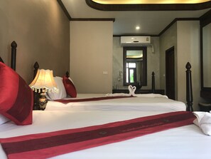 Una camera d'albergo con un letto grande, una lampada da comodino, uno specchio e un condizionatore d'aria.