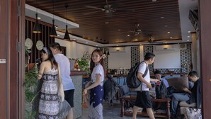 A hotel lobby with wooden ceilings, pendant lighting, and a reception desk.