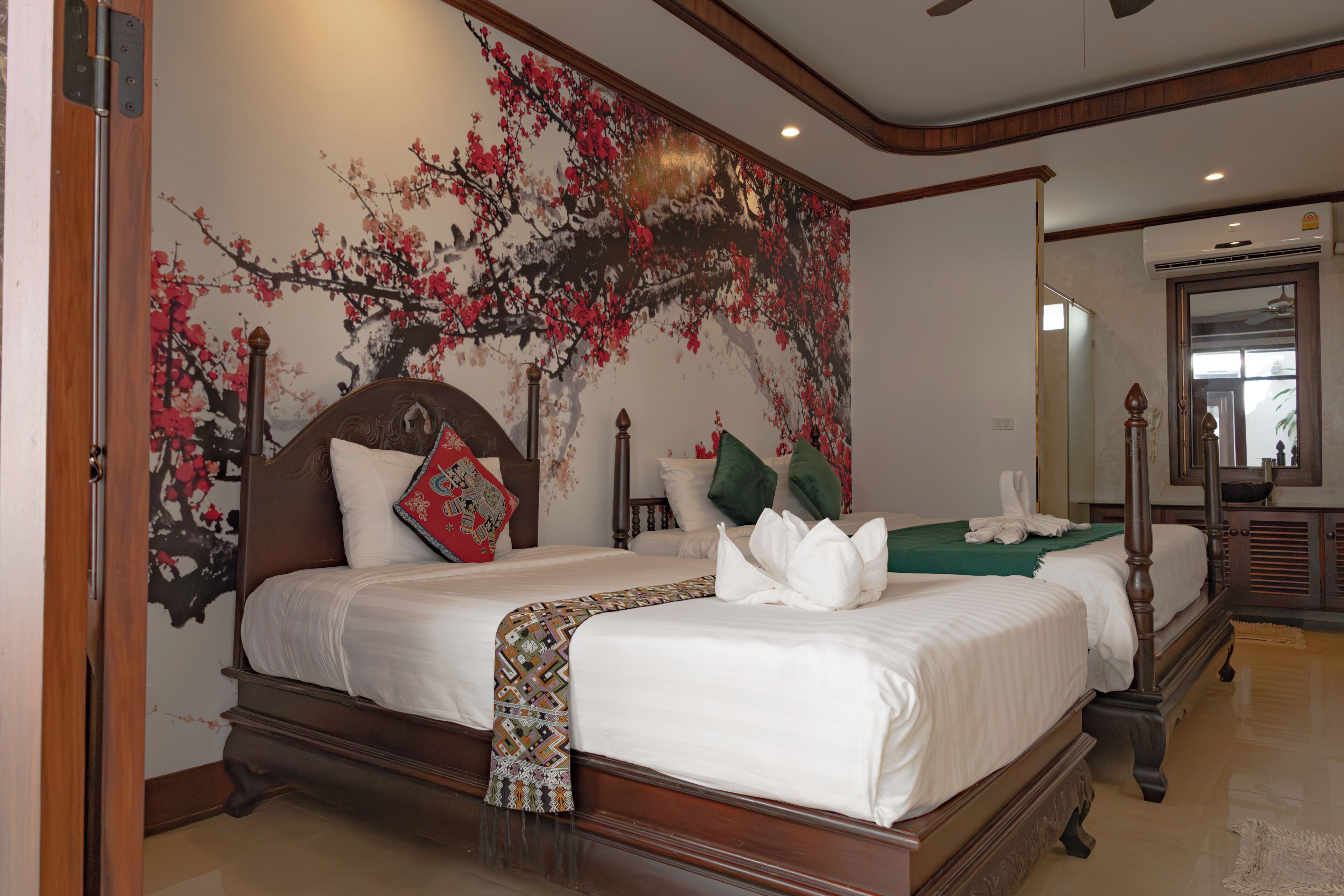 A large, ornate bed with a wooden frame and a colorful headboard, accompanied by two smaller beds.