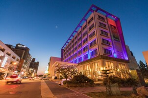 A multi-story hotel with a modern design, featuring a prominent entrance and a well-lit facade.