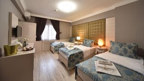 Habitació d'hotel amb dos llits, un escriptori amb làmpada, televisió i finestra amb cortines.