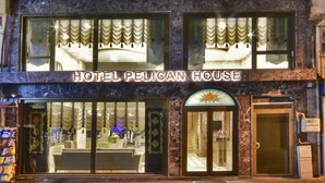 Un hotel amb diversos balcons, un vestíbul a la planta baixa amb una taquilla d'informació i un rètol que diu "HOTEL PELICAN HOUSE".