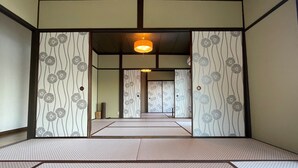 Una cambra japonesa tradicional amb terra de tatami, portes corredisses amb motius florals i un llum penjant.