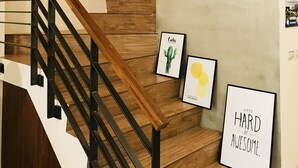 A staircase with wooden steps and black railings, a clock, and framed artwork on the walls. - Chestnut Guest House (Taitung)
