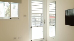 A room with a sliding glass door leading to a balcony, a mounted television, and a window with blinds. - Chestnut Guest House (Taitung)