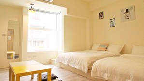 A bright, minimalist room with two beds, a small table, and a window providing natural light. - Chestnut Guest House (Taitung)