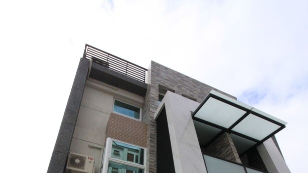 A modern multi-story building with a prominent glass facade, a brick base, and a flat roof. - Chestnut Guest House (Taitung)