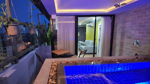 A balcony with a small table and chairs, a hanging plant, and a view of the cityscape. - Katy Resident and Spa (Siem Reap)