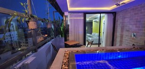 A balcony with a small table and chairs, a hanging plant, and a view of the cityscape. - Katy Resident and Spa (Siem Reap)