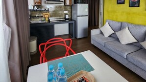A compact living space with a kitchenette, a grey sofa, and a red chair. - Katy Resident and Spa (Siem Reap)