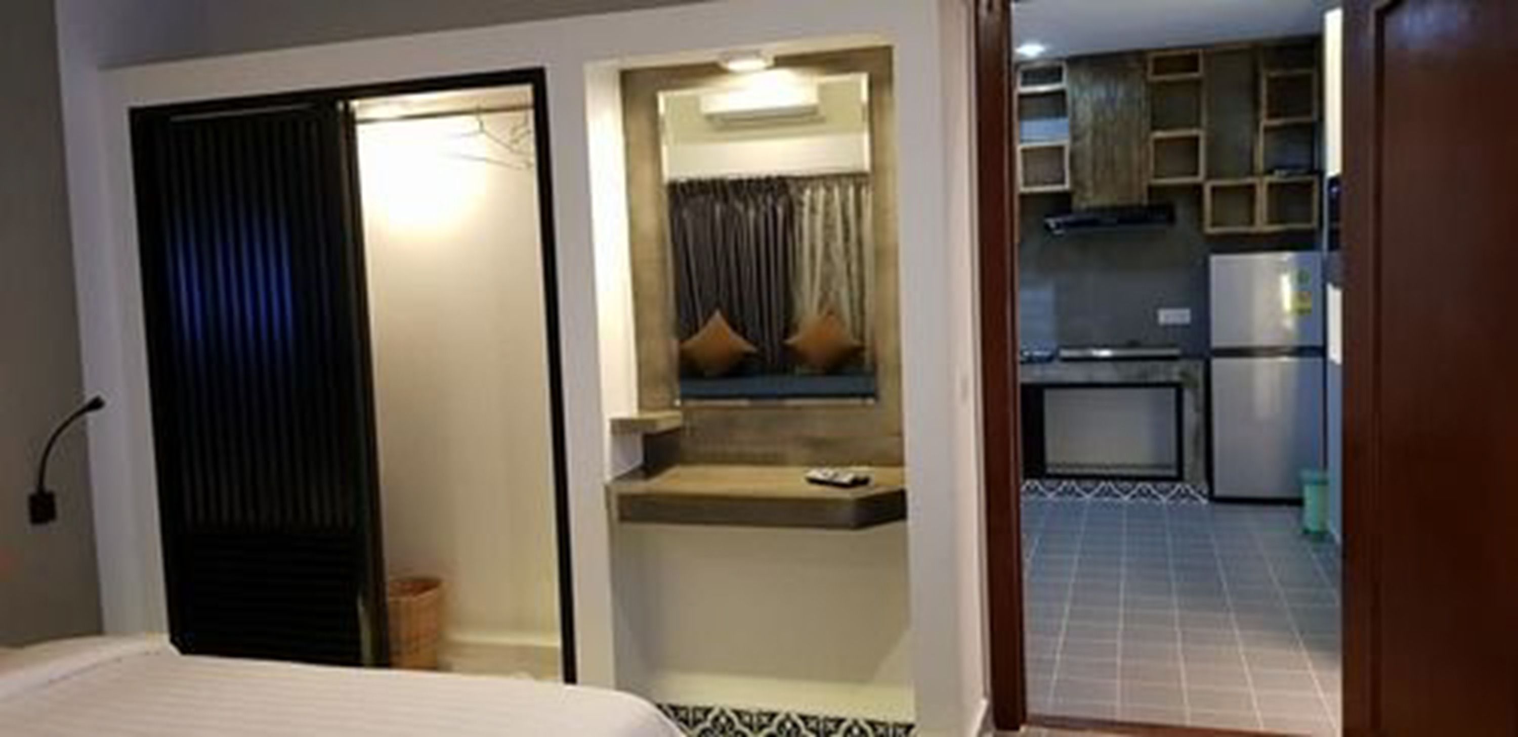 Et kompakt hotelværelse med seng, lille siddeområde med bord og et tekøkken i baggrunden.