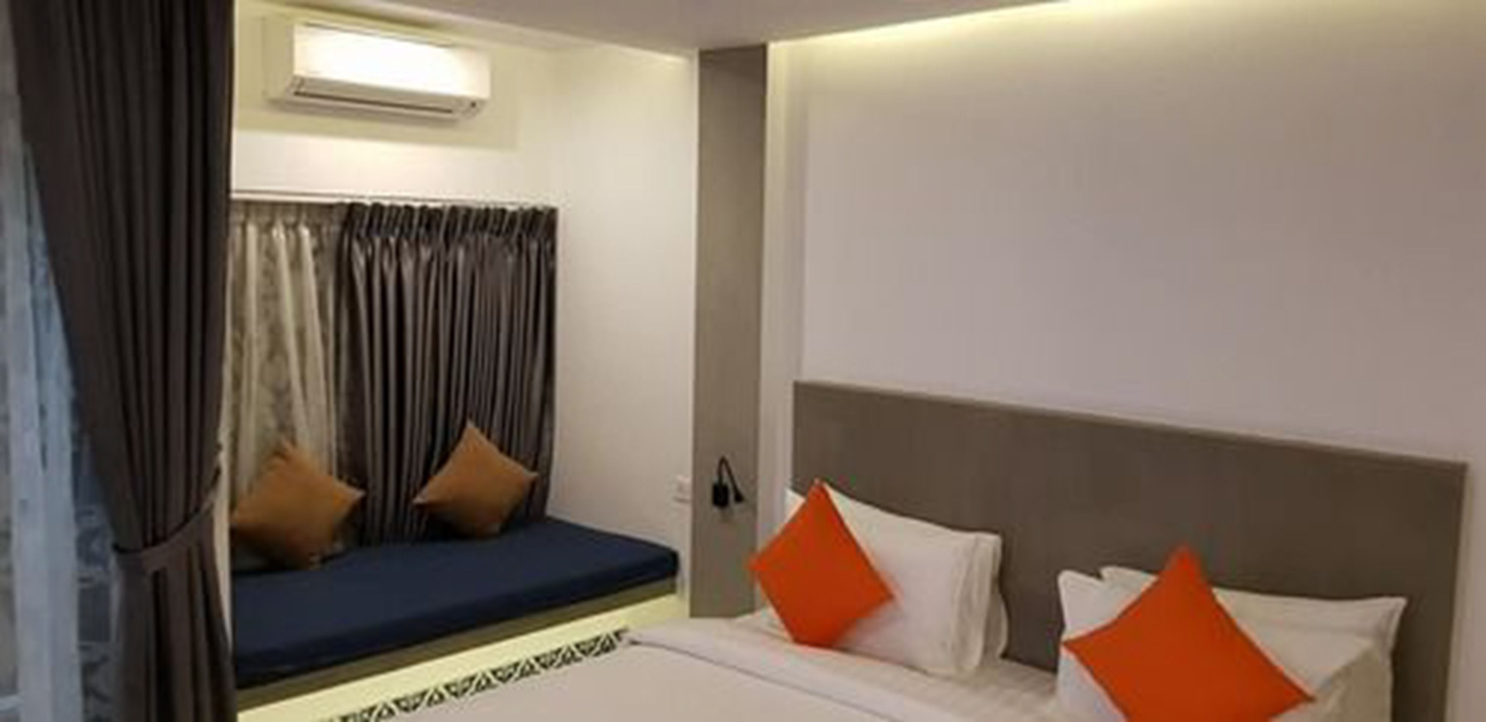 Una habitación de hotel con cama, sofá y ventana con cortinas.