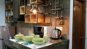 A kitchen with a refrigerator, microwave, kettle, and green bowls on the counter. - Katy Resident and Spa (Siem Reap)
