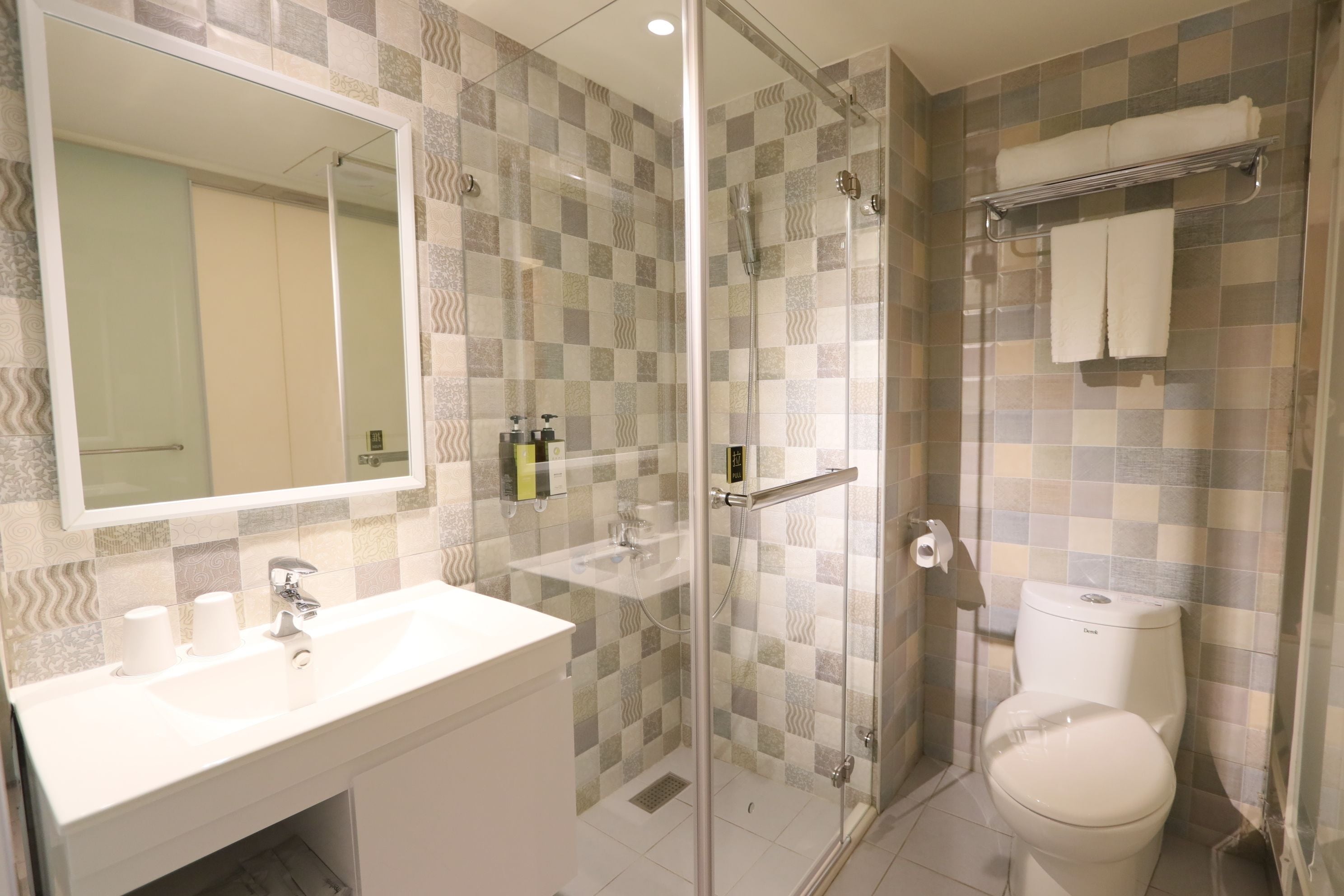 A modern bathroom with a glass shower enclosure, a white sink, and a toilet.
