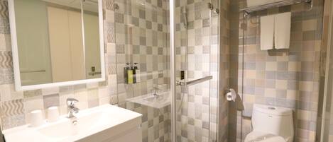 A modern bathroom with a glass shower enclosure, a white sink, and a toilet.