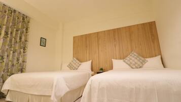 Habitación de hotel con dos camas, cabecera de madera y una mesita de noche con una planta.