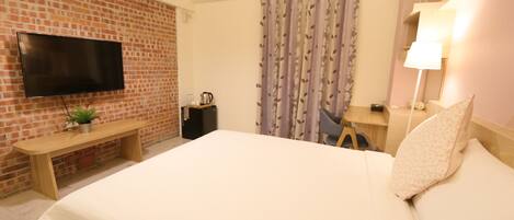 Une chambre d’hôtel avec un mur en briques, un téléviseur à écran plat, un banc en bois, un lit avec un oreiller, un rideau, une table de chevet avec une lampe et une petite plante.
