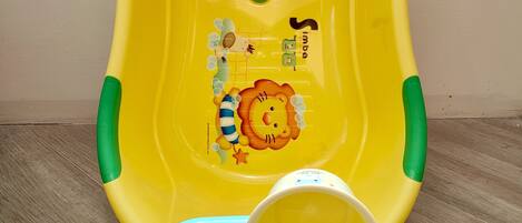 Un recipiente de plástico amarillo y verde con diseño de león, sobre un suelo de madera.