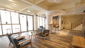 Eine großzügige Lobby mit Holzböden, einem Empfangstresen und Sitzbereichen.