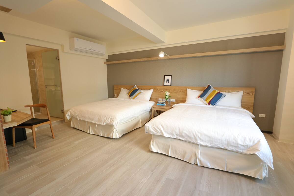 A hotel room with two beds, a desk, and a chair.