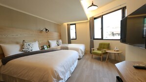 Ein Hotelzimmer mit zwei Betten, einem Fernseher, einem kleinen Tisch und einem Stuhl.
