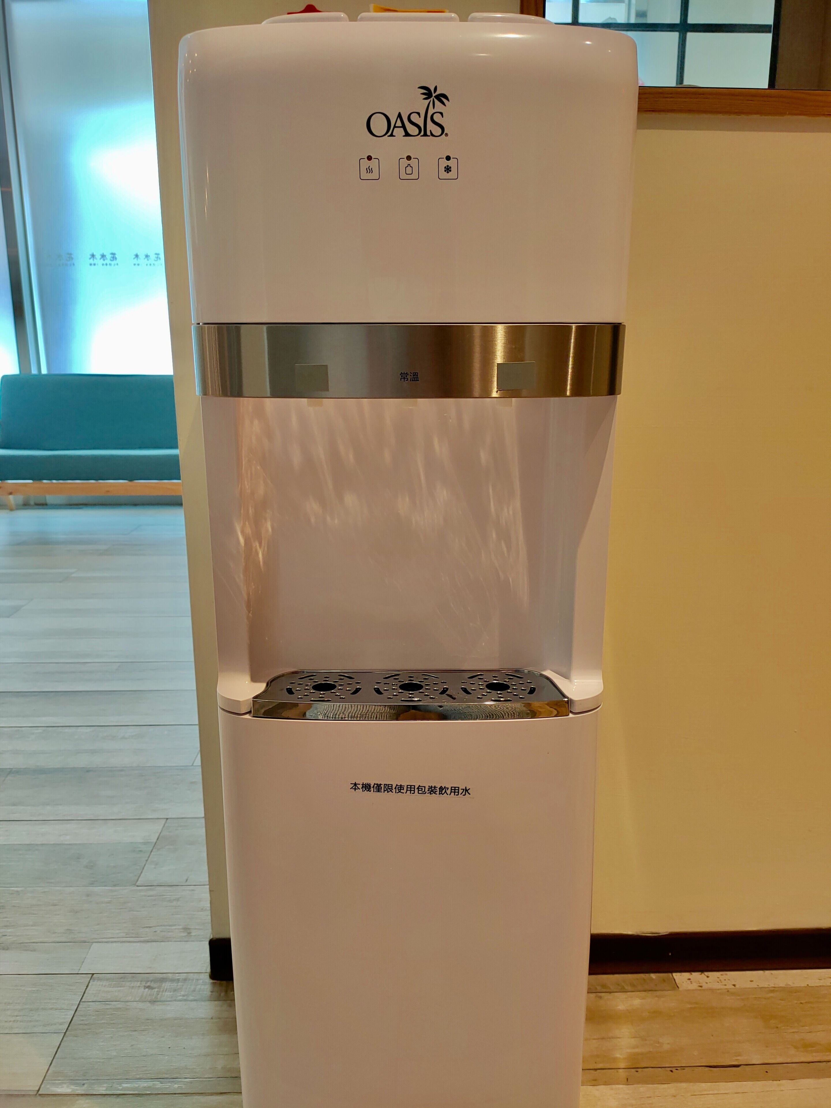 A white Oasis water dispenser with a stainless steel top and a water bottle holder.