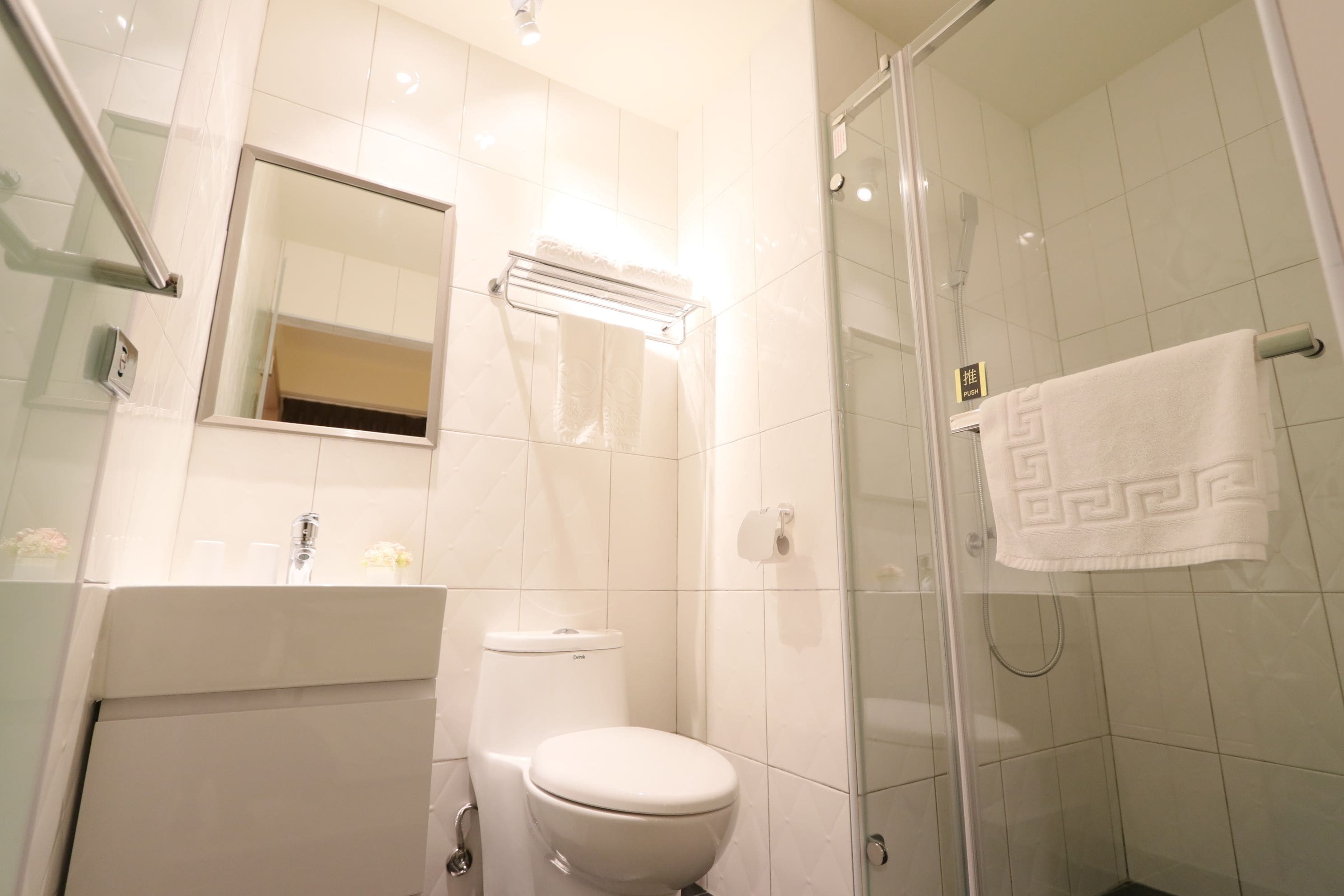 A modern bathroom with a toilet, a glass shower enclosure, and a mirror.