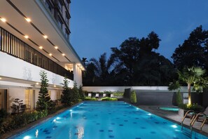 A swimming pool with a modern design, surrounded by a landscaped garden and a building with a balcony. - d'primahotel Kualanamu Medan (Medan)