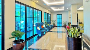 A hotel lobby with a long reception desk, large windows, and seating area. - d'primahotel Kualanamu Medan (Medan)