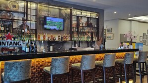 A bar area with a counter, multiple liquor bottles, and bar stools. - d'primahotel Kualanamu Medan (Medan)