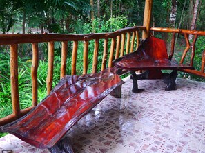 A wooden deck with a tiled floor, surrounded by lush greenery.
