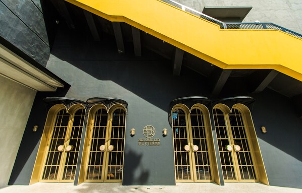A building facade with three arched windows and a yellow awning. - Cosmos Hotel Huashan Town (Taipei)