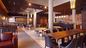 En rymlig restaurang med högt i tak, modern belysning och en bar.