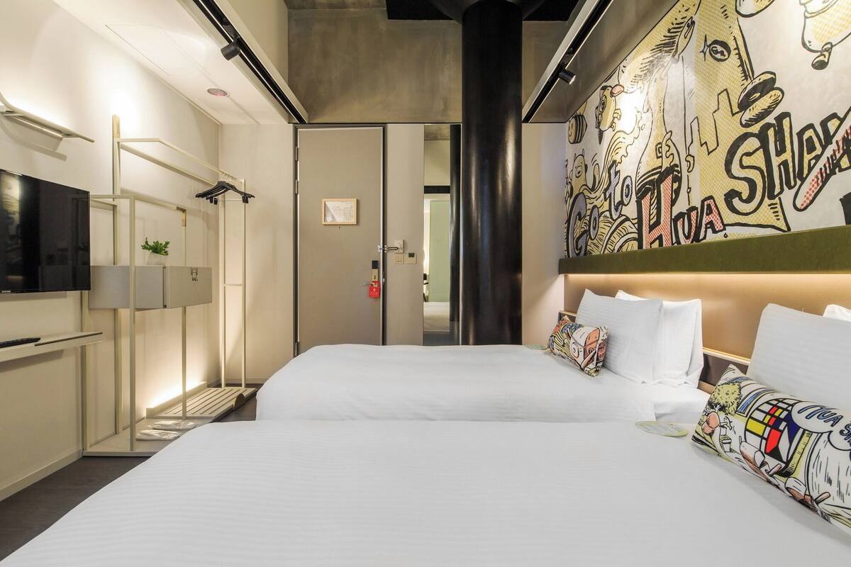 A hotel room with a large bed, a TV, a wardrobe, and a bathroom visible through an open door.