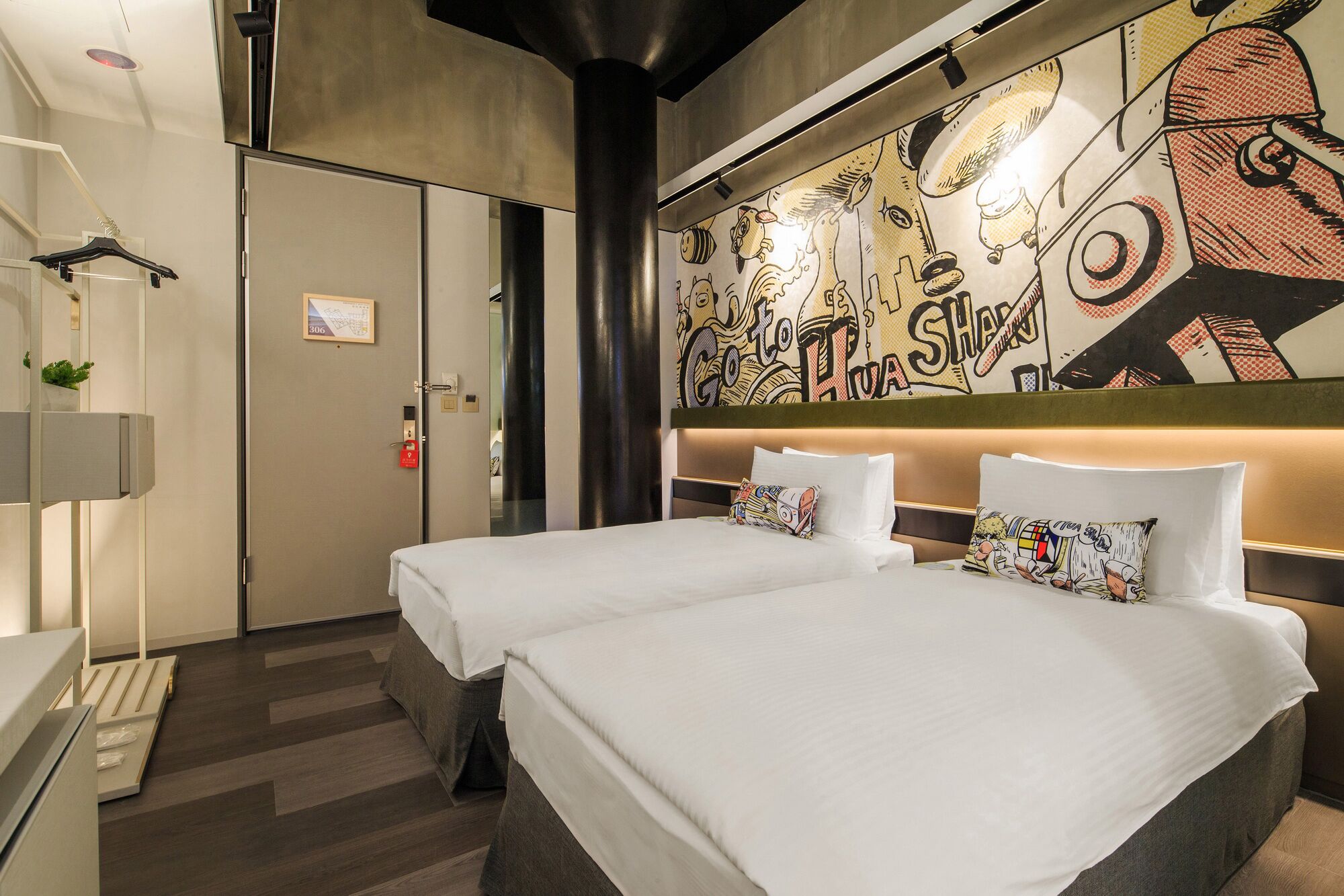 A hotel room with two beds, a large mural on the wall, and a modern design.