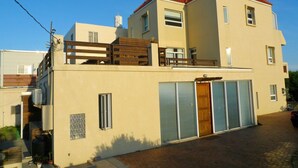 Een gebouw met twee verdiepingen, een plat dak, een balkon en een garage.