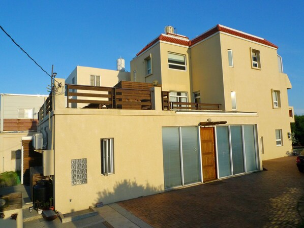 Um edifício de dois andares com teto plano, varanda e porta de garagem.