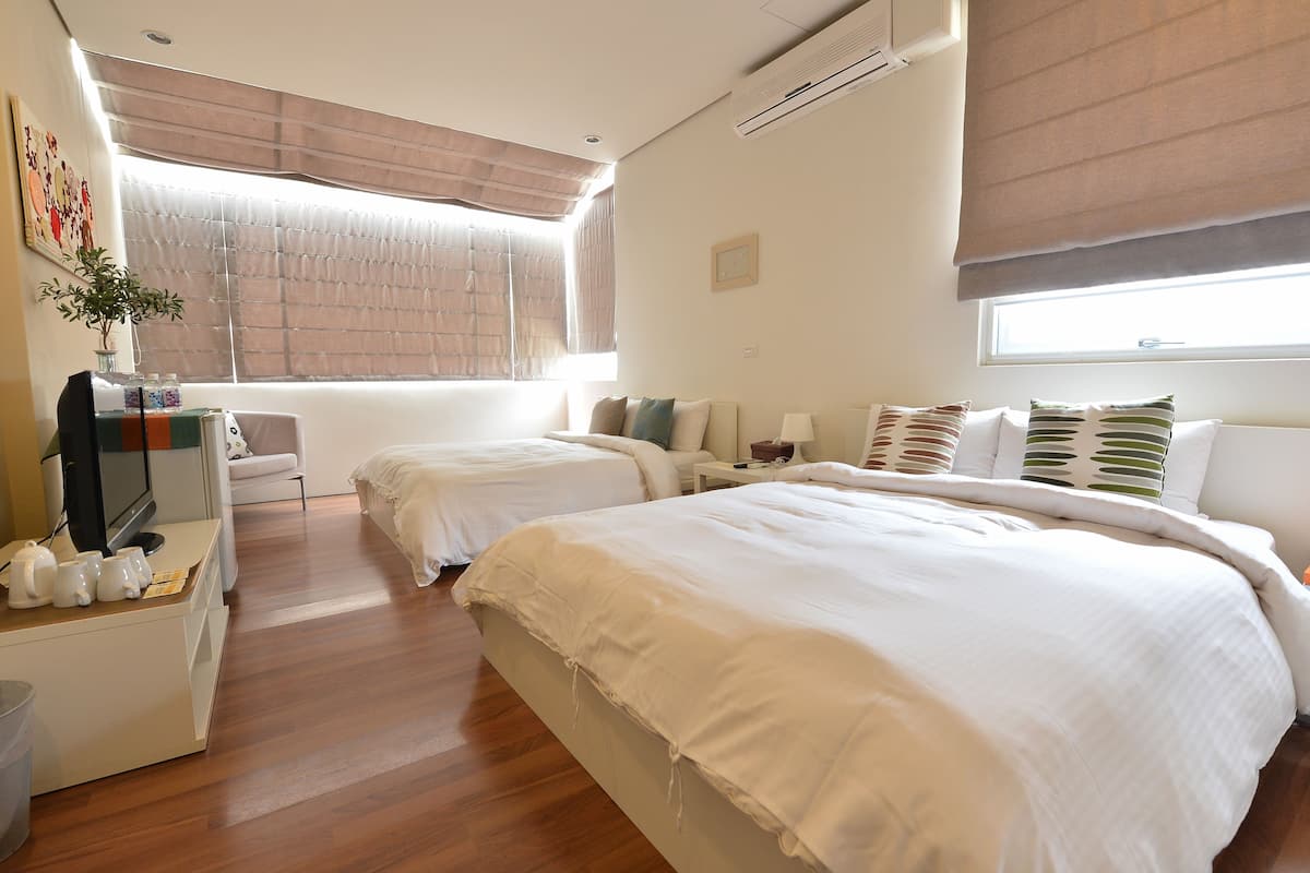 Una habitación de hotel con dos camas, un escritorio con televisión y una ventana con persianas.