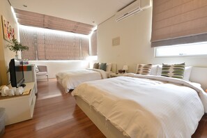 A hotel room with two beds, a desk with a TV, and a window with blinds. - Bay of Chen-Hai Penghu Homestay (Baisha)