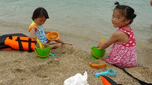 Twee kinderen spelen in het zand op het strand.