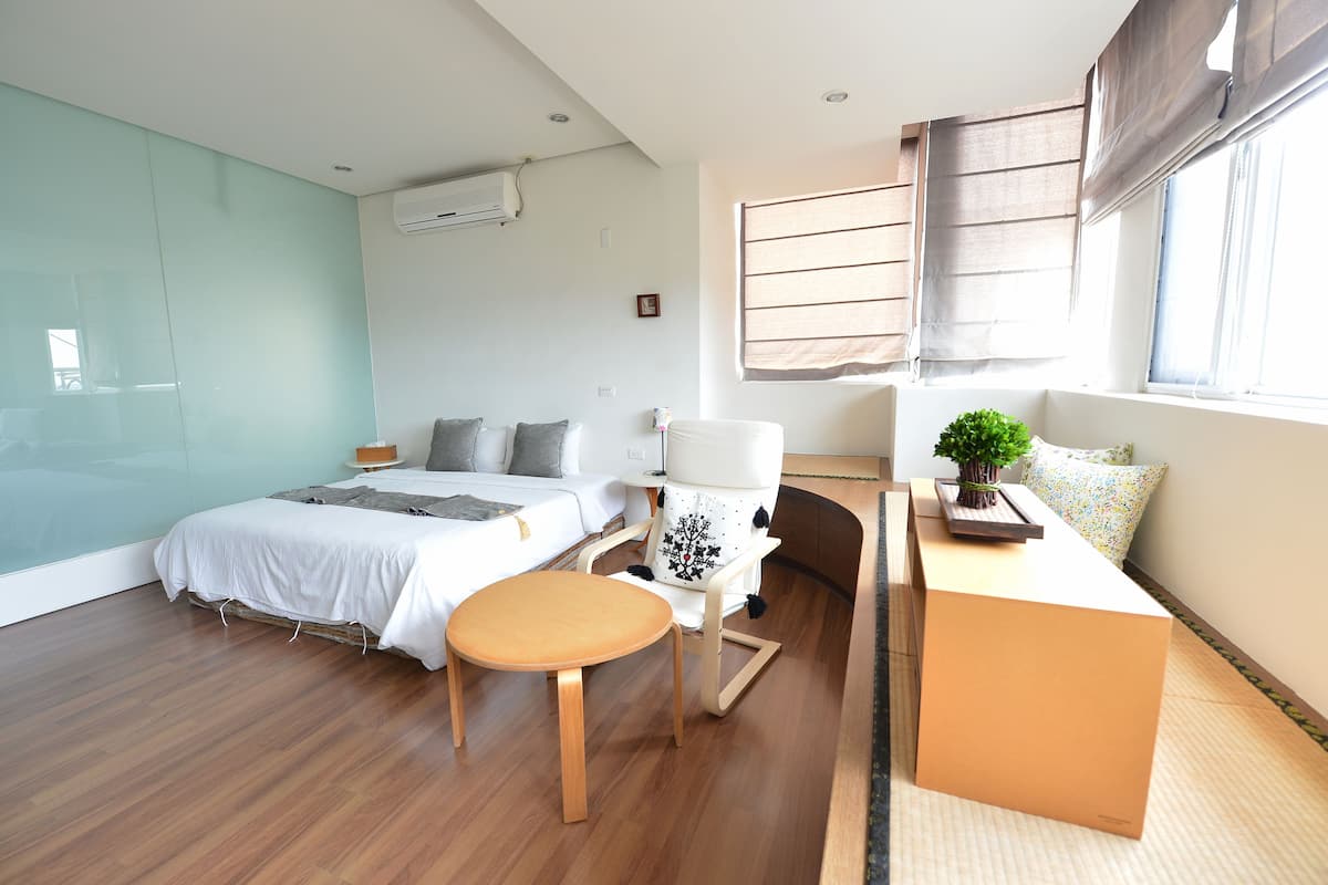 Una habitación de hotel moderna con cama, escritorio, silla y una pequeña mesa.