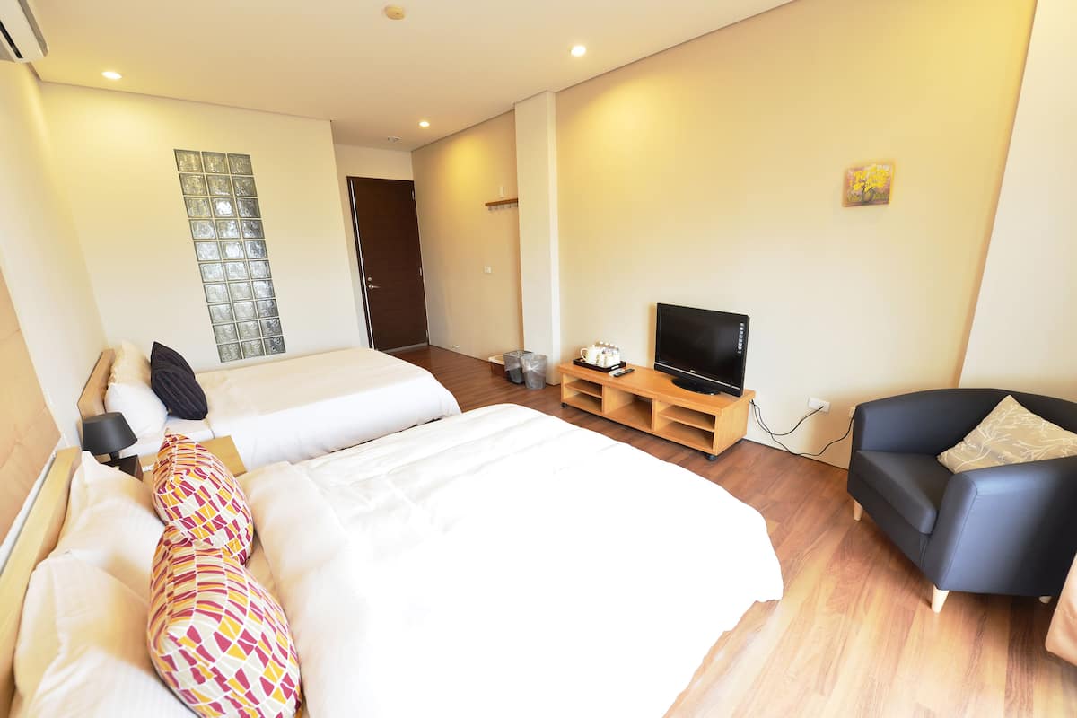 Una habitación de hotel con dos camas, un televisor, un sofá y una mesita.