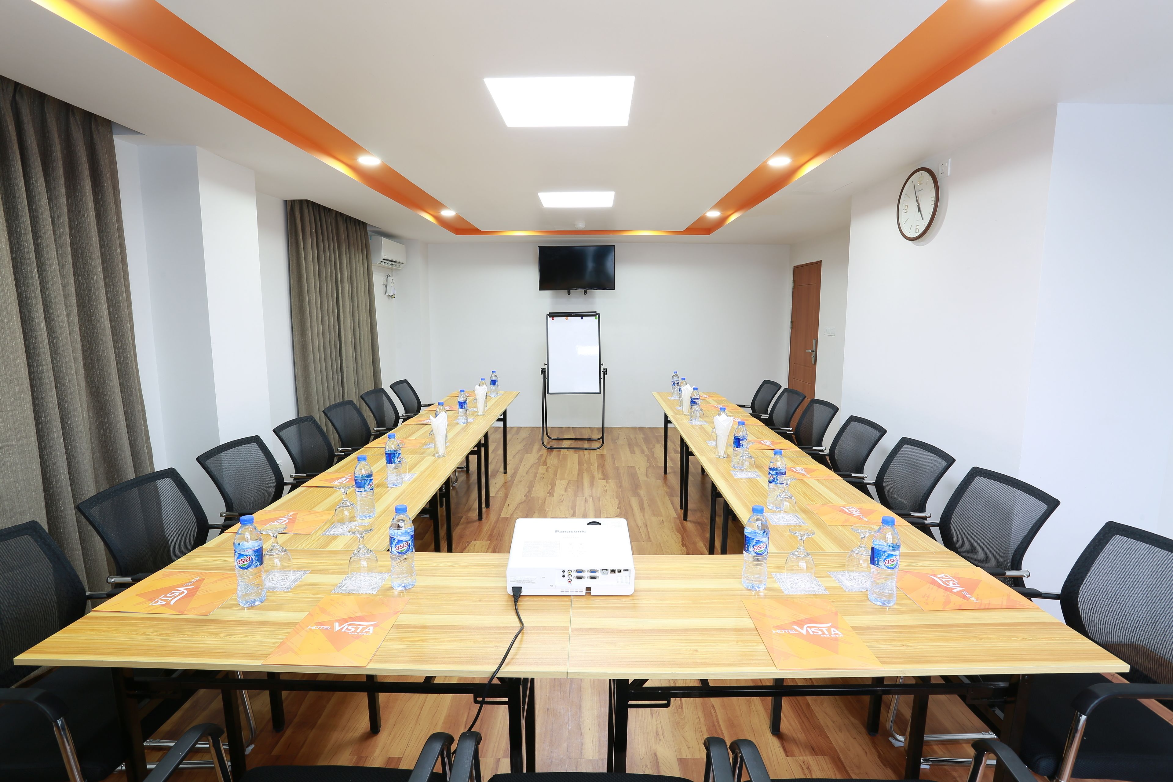 A conference room with a long table, chairs, a projector, and water bottles.