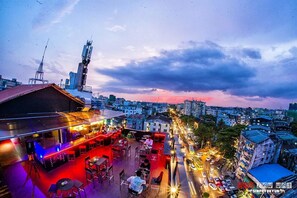 A rooftop bar with outdoor seating and a city view at dusk. - Hotel Vista (Yangon)