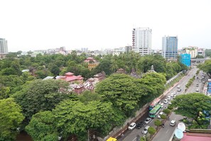 A cityscape with dense greenery, a river, and a mix of modern and traditional buildings. - Hotel Vista (Yangon)