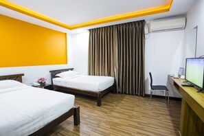 A hotel room with two beds, a desk with a computer, an air conditioner, and a TV. - Hotel Vista (Yangon)