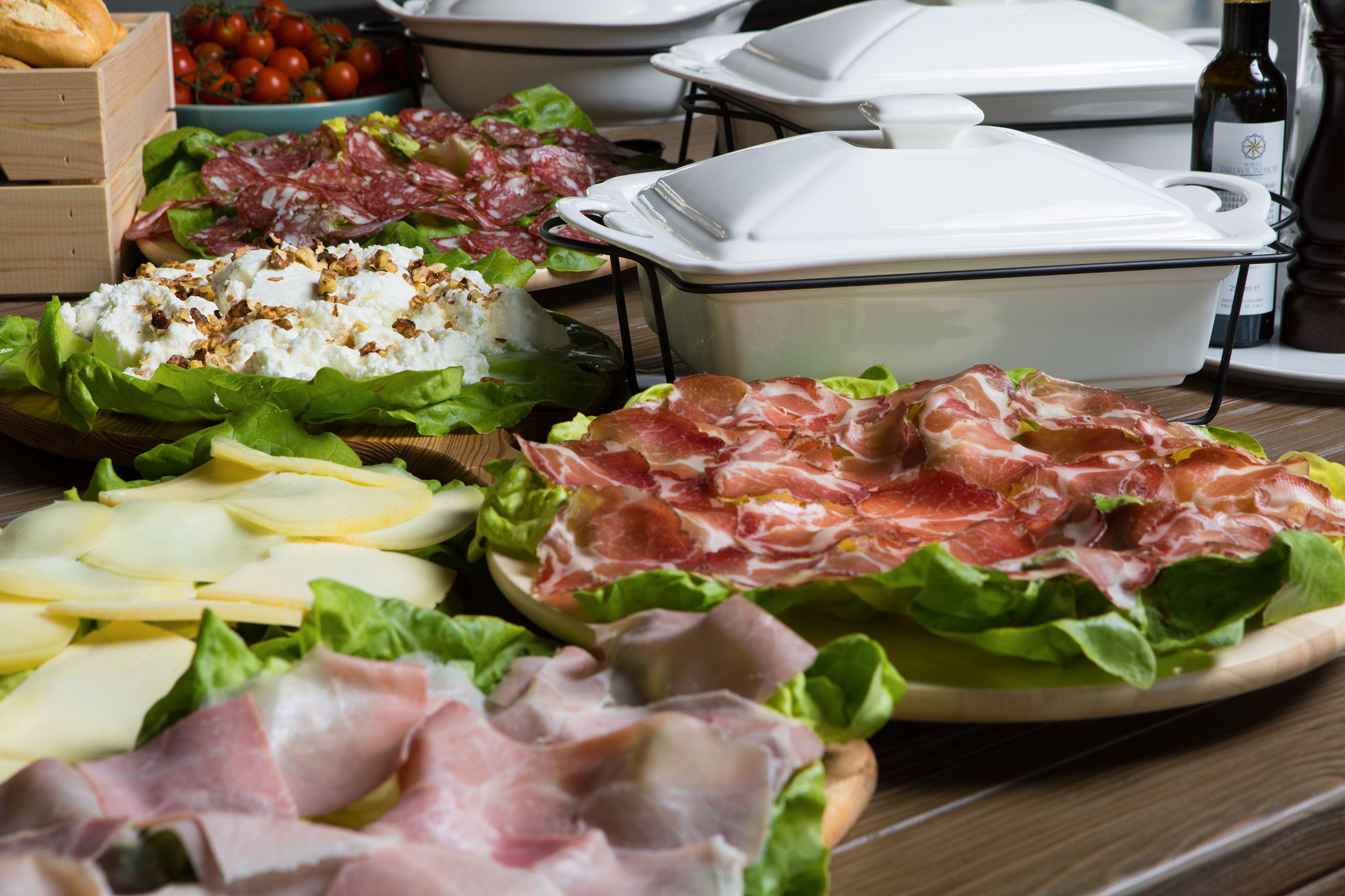 A variety of food items including cheese, cured meats, and vegetables on a wooden table.