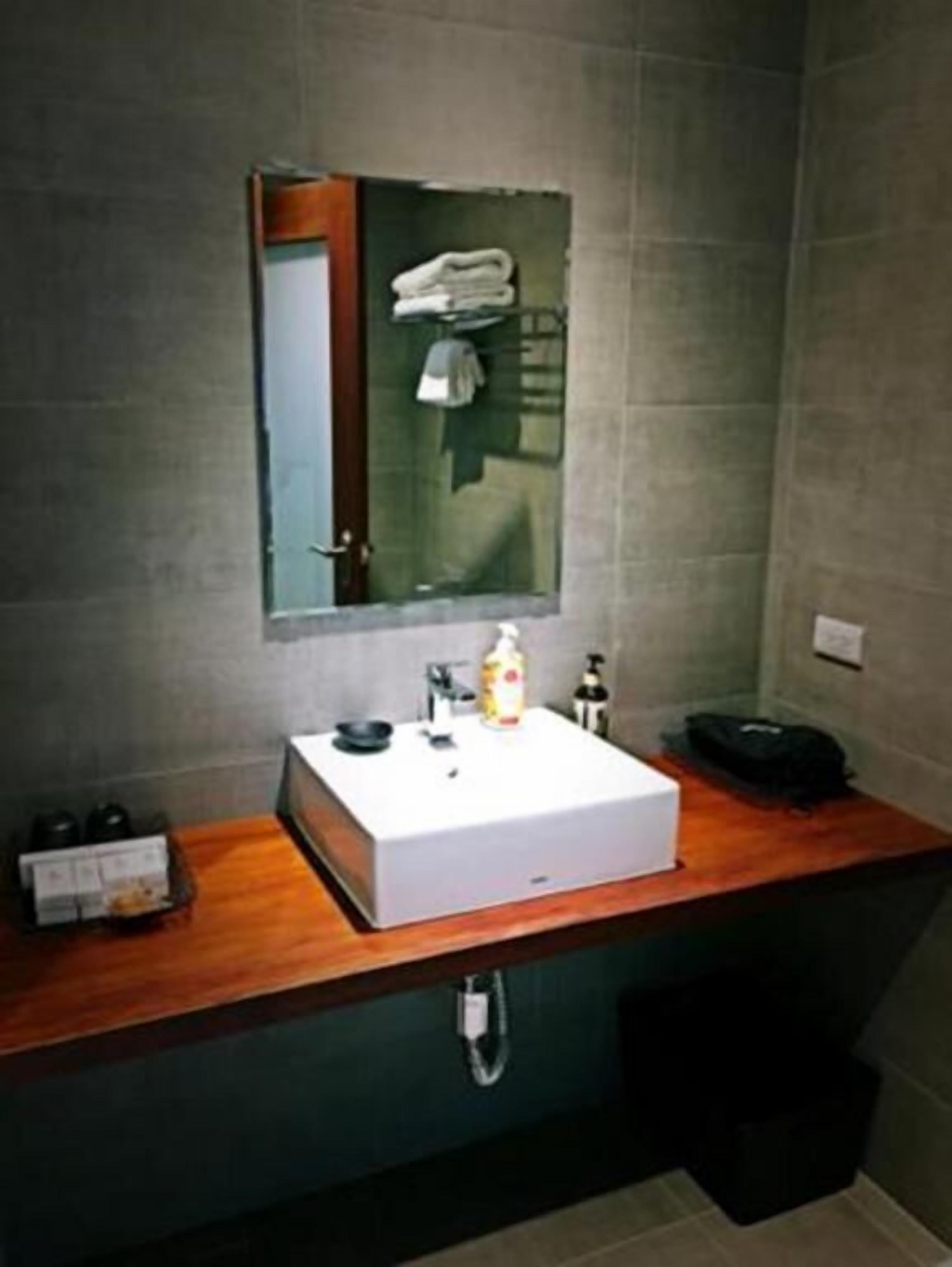 A bathroom with a white sink, a mirror, and a wooden countertop.