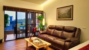 Uma sala de estar moderna com um sofá de couro, uma mesa de centro de madeira e uma janela grande com vista para o exterior.